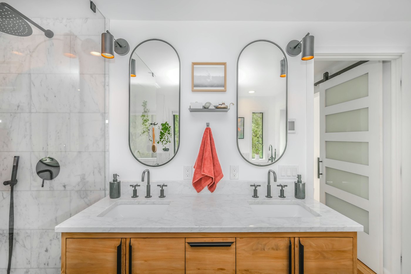 Baño con dos espejos ovalados sobre un mueble de madera, espejos a medida en Chile